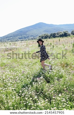beautiful woman traveler walks through a field of chamomile flowers