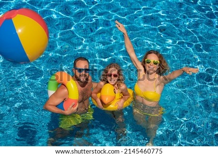 Happy family playing in outdoor pool. People having fun on summer vacation. Healthy lifestyle concept