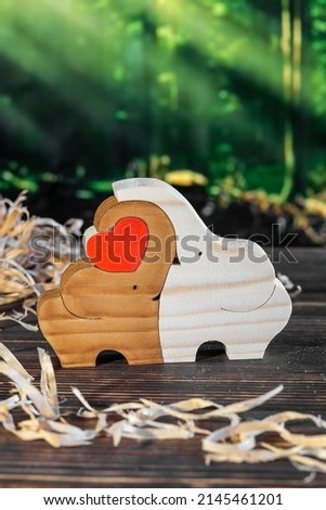 Wooden puzzle in the form of a family of handmade elephants on the background of the forest.