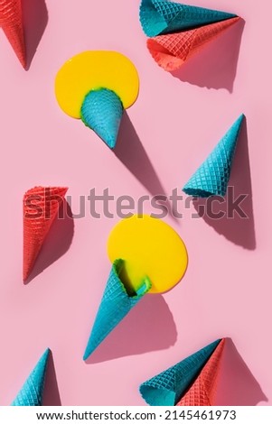 Bright composition with melted ice cream and colorful waffle cones on a pink background.