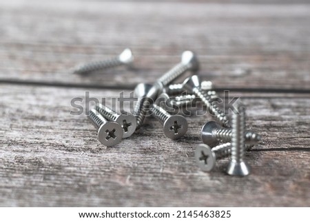 Tapping screws made of steel on wood background, metal screw, iron screw, chrome screw, screws as a background, wood screw, concept industry. copy space for text. Royalty-Free Stock Photo #2145463825