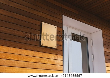 Photo of a wooden wall with white door and golden copy space plate. Royalty-Free Stock Photo #2145466567