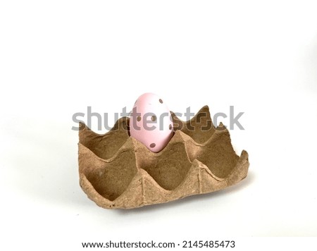 Pink Easter egg in a cardboard stand on a light background.