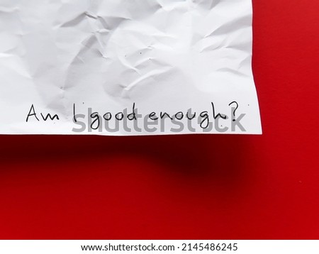 On copy space red background, crumpled paper with handwritten AM I GOOD ENOUGH? - negative self talk showing self doubt, inner voice with critical judgement - feeling not good enough Royalty-Free Stock Photo #2145486245