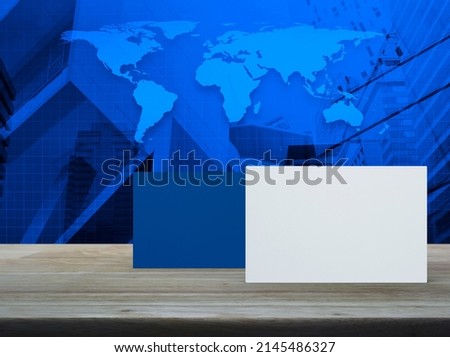 Blank white and blue business name card mockup on wooden table over world map, city tower and skyscraper, Elements of this image furnished by NASA