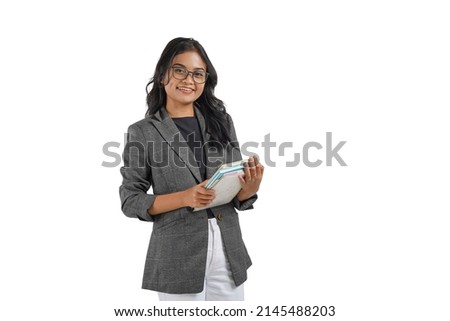 Portrait of a young Asian business woman standing  in front of white background, smiling and carrying her books. She looks confident, happy and optimistic.