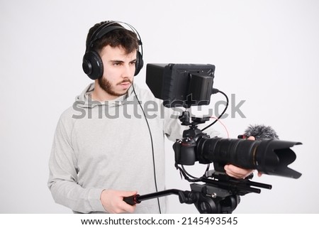 portrait of a young man video camera operator making interview in professionnal broadcast tv movie studio film production with a dslr camera