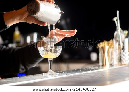 bartender is preparing a cocktail. Bartender pours a cocktail Royalty-Free Stock Photo #2145498527