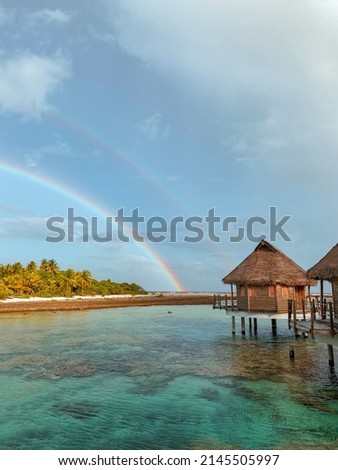 Tropical landscape with the palm trees, overwater bungalow and beautiful rainbows over the lagoon of the atoll of Tikehau, Tuamotu, French Polynesia, South Pacific Royalty-Free Stock Photo #2145505997