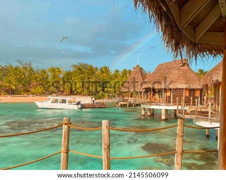 Tropical landscape with the palm trees, overwater bungalow and beautiful rainbows over the lagoon of the atoll of Tikehau, Tuamotu, French Polynesia, South Pacific Royalty-Free Stock Photo #2145506099