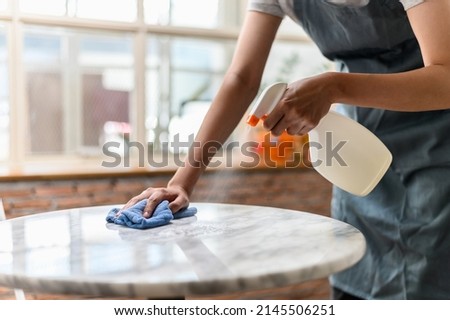Close up hand of woman cleaning marble stone table using clothes and cleaning solution. Royalty-Free Stock Photo #2145506251
