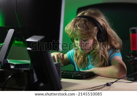 Child plays a video game on the pc computer screen. Gamer play computer games. Neon lighting. Social network for kids.