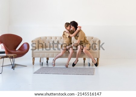 Emotional little school girl together with mom spend active weekend with happy young mom. Energetic family of two indulge together in the living room
