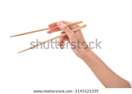 female hand holds Wooden chopsticks isolated on white background. Royalty-Free Stock Photo #2145522339