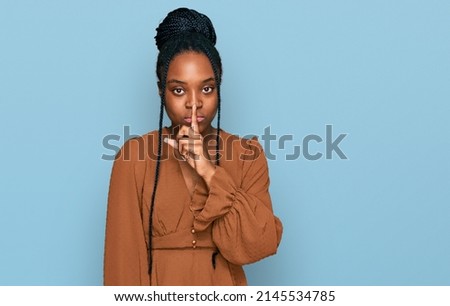 Young african american woman wearing casual clothes asking to be quiet with finger on lips. silence and secret concept.  Royalty-Free Stock Photo #2145534785