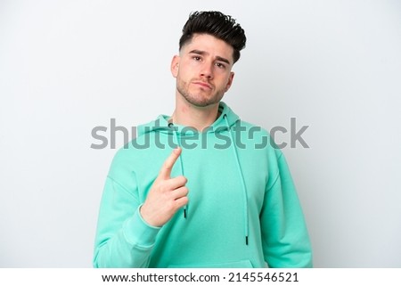 Young caucasian man isolated on white background frustrated and pointing to the front