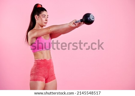 Every challenge is meant to change you. Studio shot of a sporty young woman exercising with a kettlebell against a pink background.