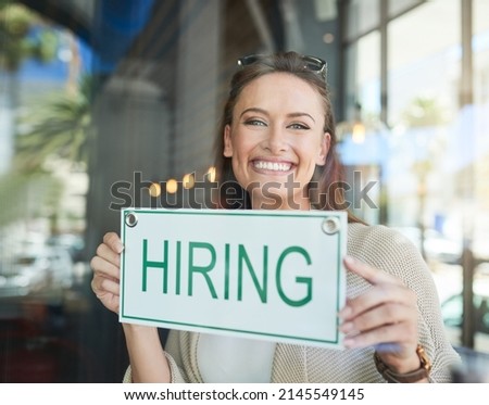 Were hiring. Portrait of a young entrepreneur holding a hiring sign in her business.