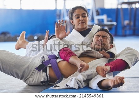 Shes got him right where she wants him. Cropped shot of two young martial artists practicing jiu jitsu in the gym. Royalty-Free Stock Photo #2145549361