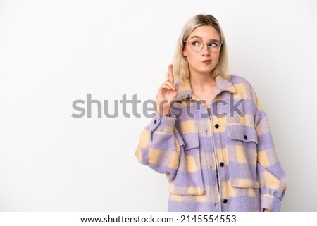 Young caucasian woman isolated on white background with fingers crossing and wishing the best