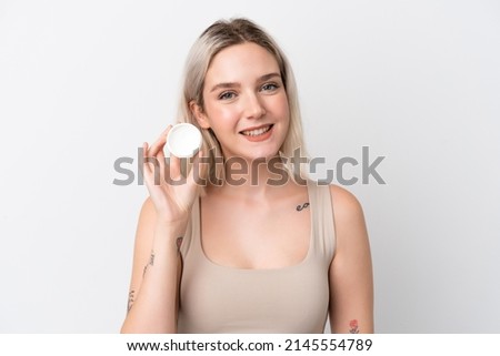 Young caucasian woman isolated on white background with moisturizer and happiness