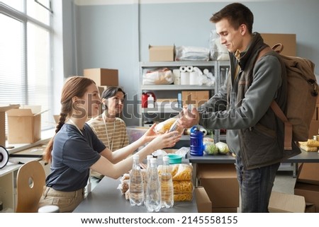 Side view portrait of young woman giving out donations while volunteering at help center for refugees Royalty-Free Stock Photo #2145558155