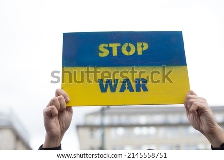 Demonstrator holding sign stop war placard. Ukraine war crisis. Anti war protests in Germany