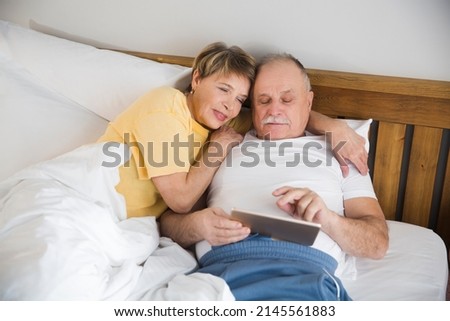healthy seniors lifestyle. a loving elderly couple use a tablet and watch videos in the morning in bed 