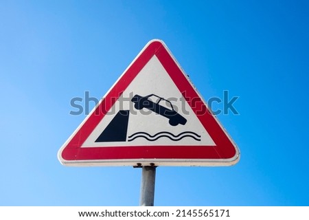 Trangular road sign, car falling into water.