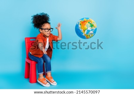 Photo of little girl playing with geography planet globe throwing in away fool around isolated on blue color background