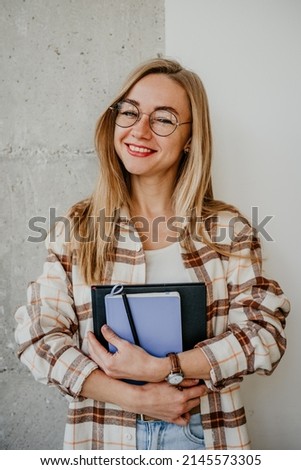 Portrait of happy young woman student in glasses with notebooks in hands