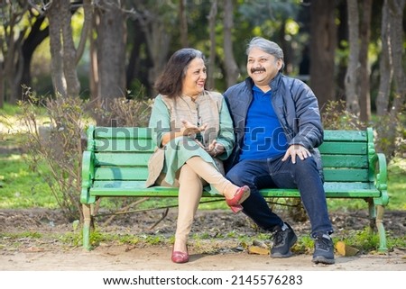 Happy Indian or asian senior couple talking laughing while sitting on the bench, Old man and woman relaxing at park spend time together, relationship and people concept. Royalty-Free Stock Photo #2145576283