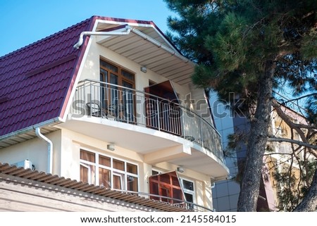 Balcony building with purple roof against blue sky. Fir tree near the house. Pension in the resort town. Royalty-Free Stock Photo #2145584015
