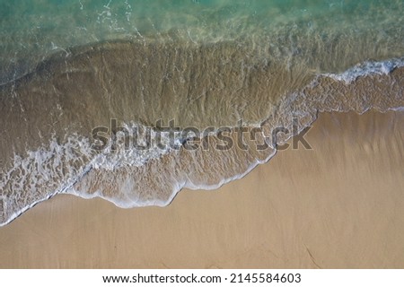 Aerial drone view taken directly above of a pure white sand beach facing waves breaking along the shoreline of a lagoon. That image was taken in Bali Indonesia. Royalty-Free Stock Photo #2145584603