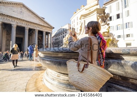 Young female traveler photographing famous Panthenon temple and fountain in Rome. Concept of happy vacations and visiting famous landmarks in Rome. Woman with colorful shawl in hair