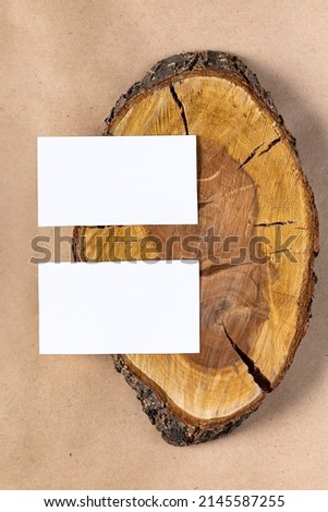 empty white business card mock up on wooden cut tree section on beige background. Flatlay, top view with copyspace, mock up. Minimal boho style