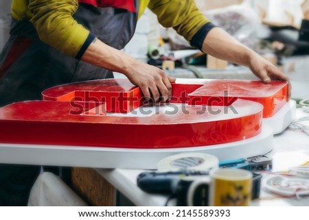 Young worker collects an advertising sign Royalty-Free Stock Photo #2145589393