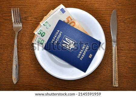 The Ukrainian passport lies on a plate in which various currencies of the world are enclosed. The photo implies the migration of Ukrainian refugees to different countries of the world