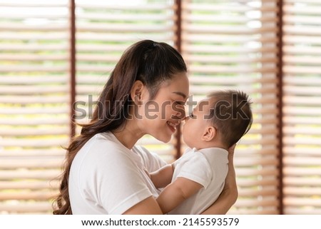 Asian mom holding her baby newborn in hand and kissing on baby nose sweet and lovely.Good moment of Happy mother and infant baby looking together smile with love.Mother and baby newborn Concept