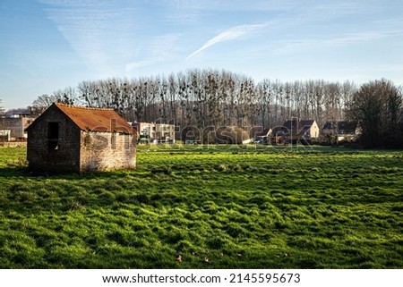 landscape view of a meadow with small stable