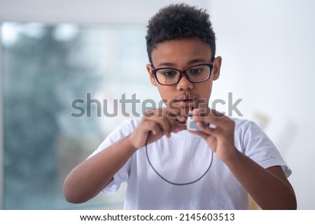 A waist up picture of a boy with a usb cable in hands