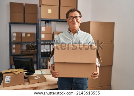 Senior man working at small business ecommerce holding carboard bx smiling with a happy and cool smile on face. showing teeth.  Royalty-Free Stock Photo #2145613555