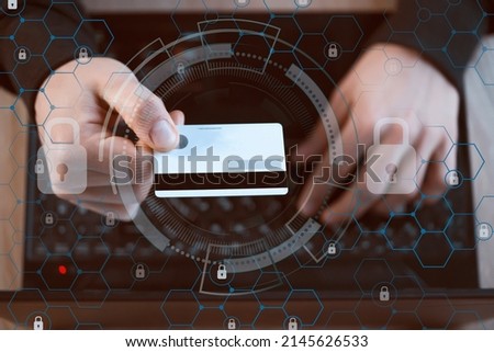 A man holds a bank card in his hand and types on a laptop keyboard, top view. Businessman makes banking transactions online, padlock sign, scheme drawn over.