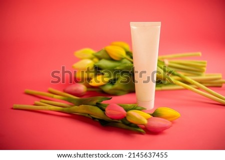 Mockup of beauty cosmetic makeup bottle product with skincare healthcare concept on pink background with tulips. High quality photo