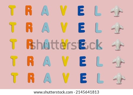 Word Travel spelled with vivid colorful foam letters on a pink background with copy space and a small toy plane. Creative vacation and visit the world cocept. Greeting summer card.