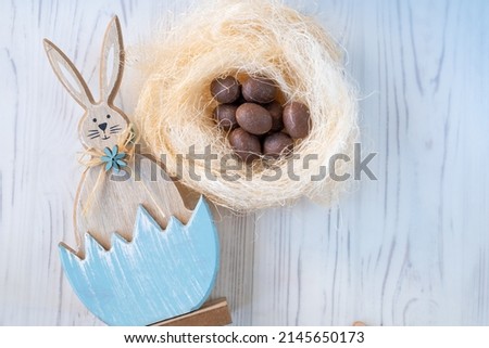 with chocolate eggs and a rabbit on a white wooden background. The concept of the Easter holiday