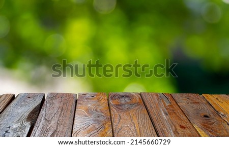Old teak wood empty table in front of green bokeh background for display of product