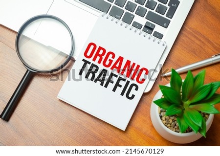 On a light background, black pencils, black paper clips, a pen and a sheet of white paper with the text ORGANIC TRAFFIC.