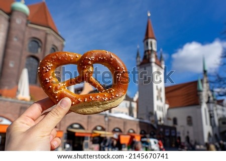 holding bayern style pretzel on the victuals market with altes rathaus background in munich Royalty-Free Stock Photo #2145670741
