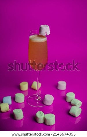 Fruit cocktail with marshmallows on a colored background. Party concept